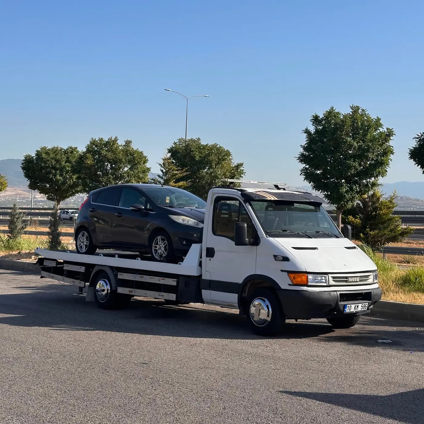 Sahil yolunda arızalanan otomobilin çekiciyle taşınması